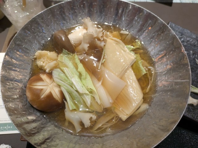Mushrooms, tofu skin, and more cooking in broth in the hot pot