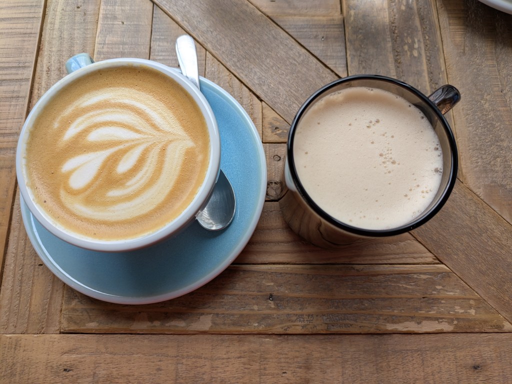 A cafe latte and a chai latte on a wooden table