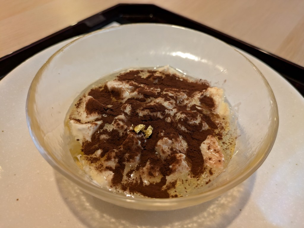 A dish of a creamy dessert topped with cocoa powder and coffee powder
