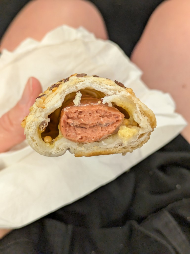 Inside a sausage roll, with a sausage on a bed of mustard