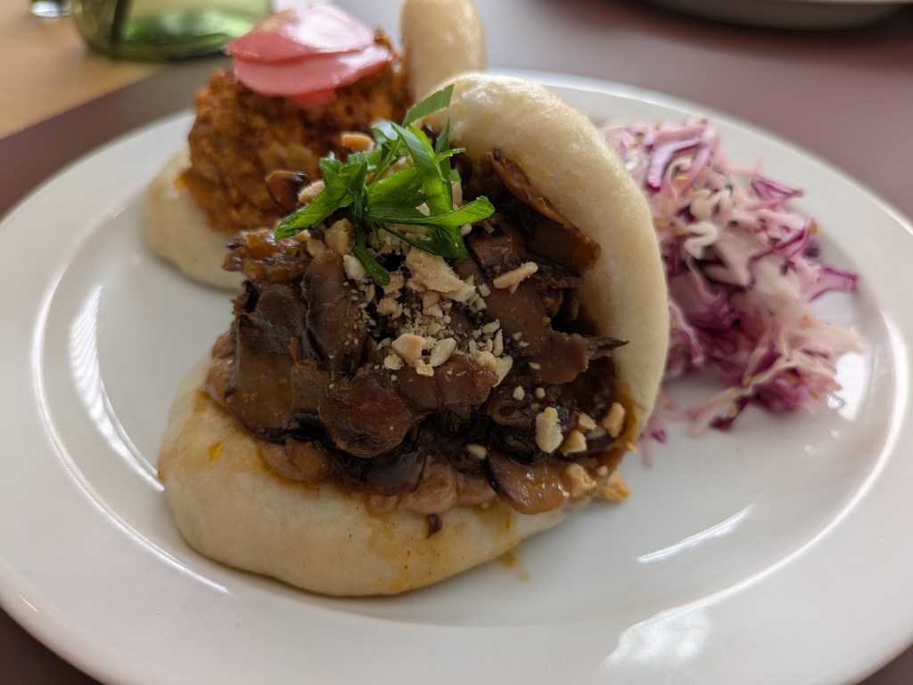 A fluffy bao bun filled with saucy mushrooms