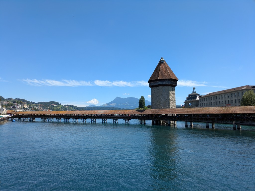Chapel Bridge in Luzern, a covered pedestrian bridge across the river, with mountains in the background