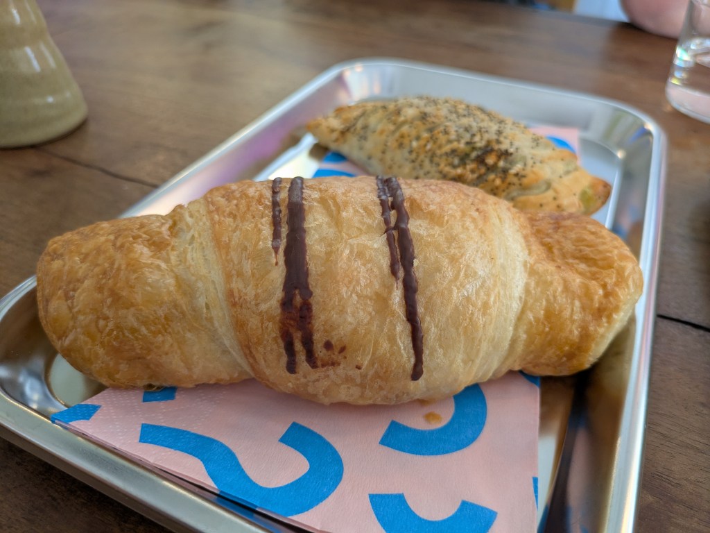 A bready looking croissant with some chocolate drizzles