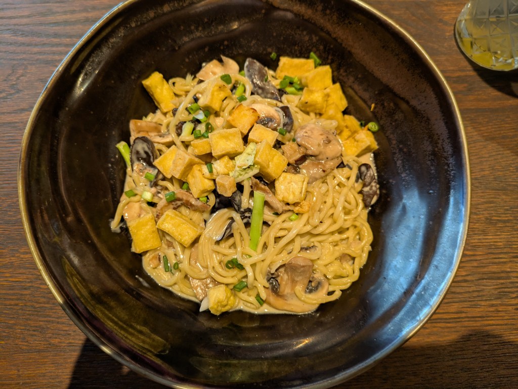 A big bowl of carbonara topped with tofu cubes and mushroom