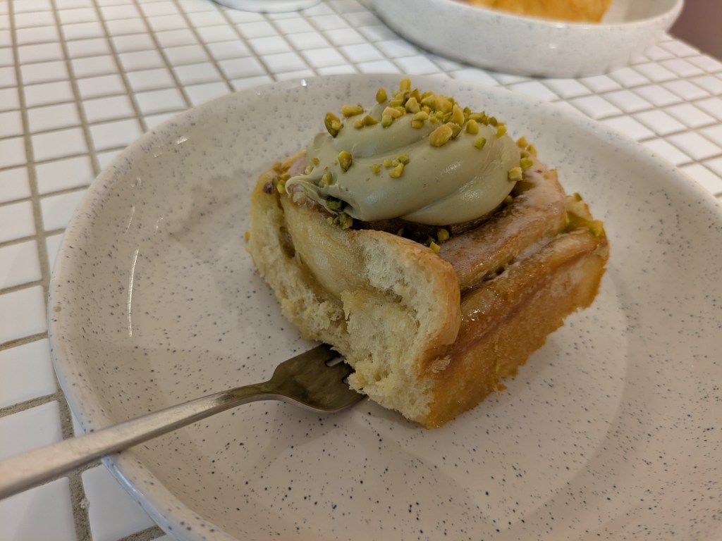 Cinnamon roll topped with a big dollop of pistachio cream and chopped pistachios