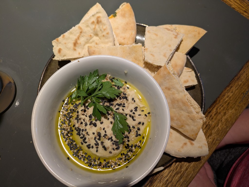 A bowl of hummus with shards of pita