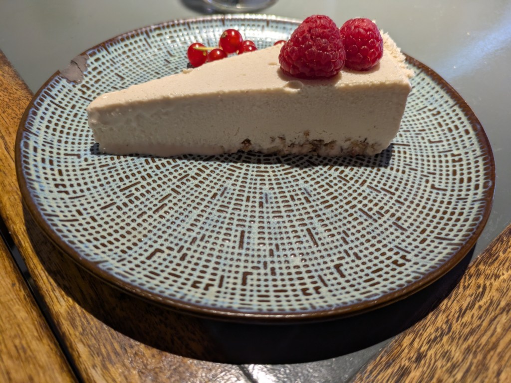 A slice of pale cheesecake topped with raspberries
