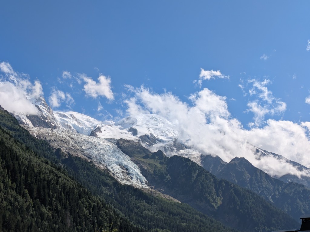 Snowy mountain peaks shrouded in cloud below a bright blue sky