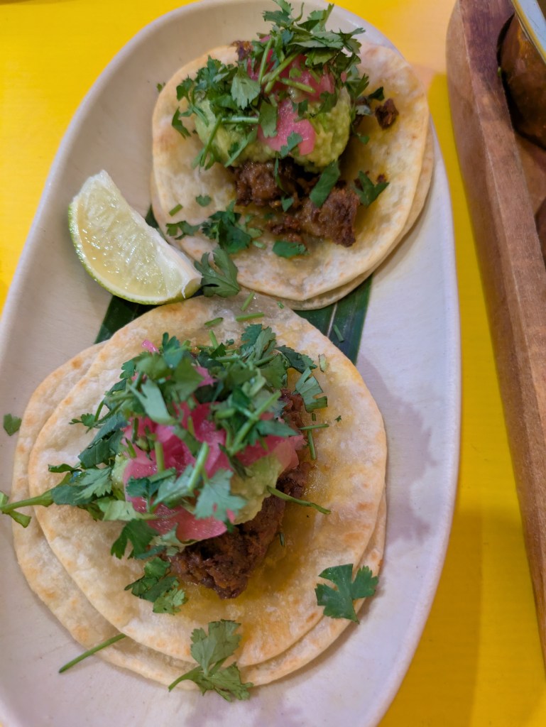 Two tacos topped with mock meat, guacamole, and garnishes