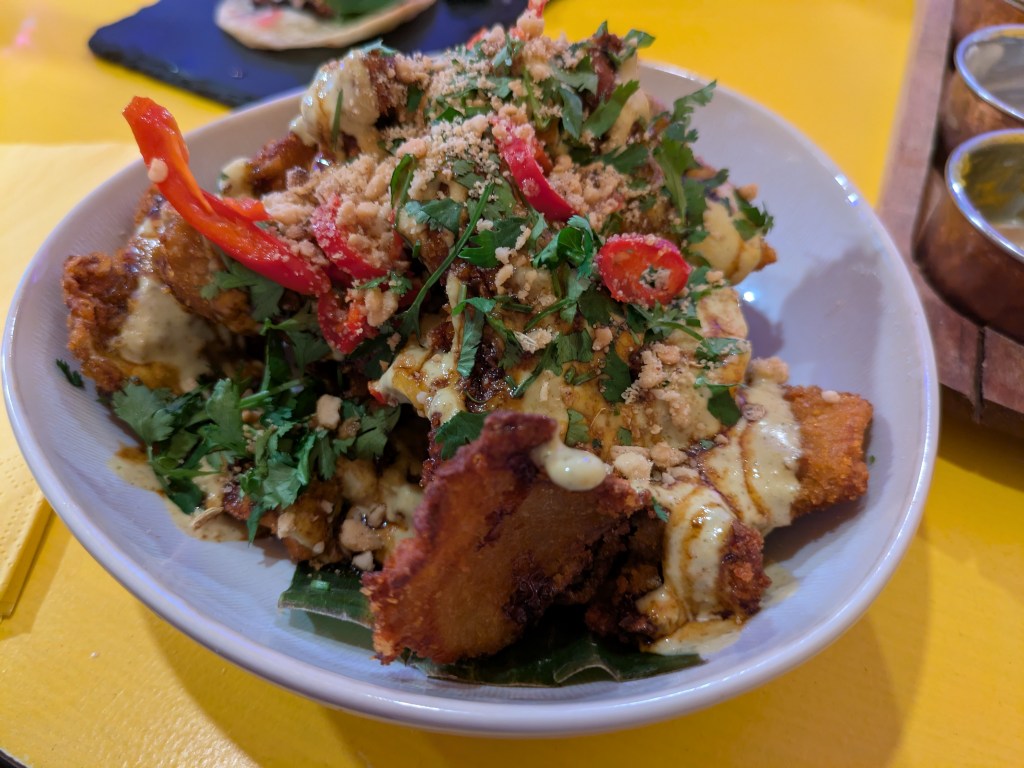 A bowl of battered fried mushrooms topped with creamy sauce and garnishes