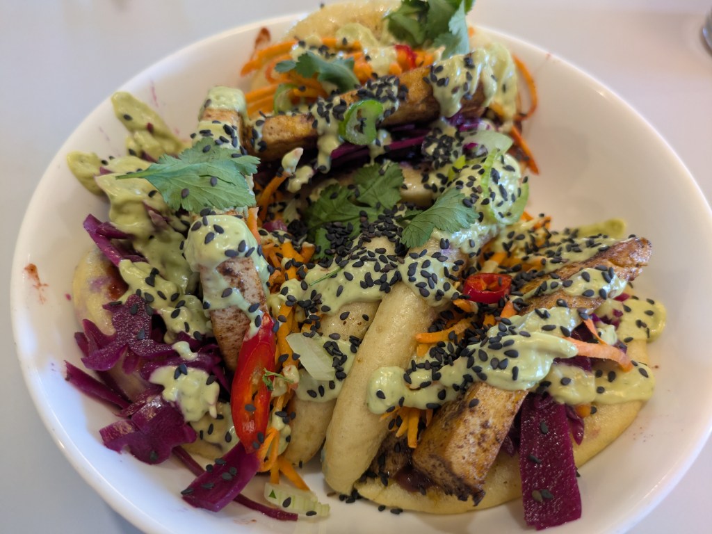 Three bao buns bursting with an array of fillings and sauces