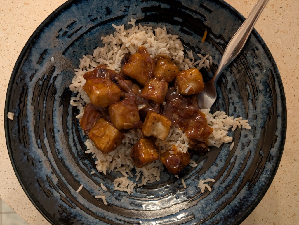 Rice topped with chunks of tofu in a sticky dark sauce
