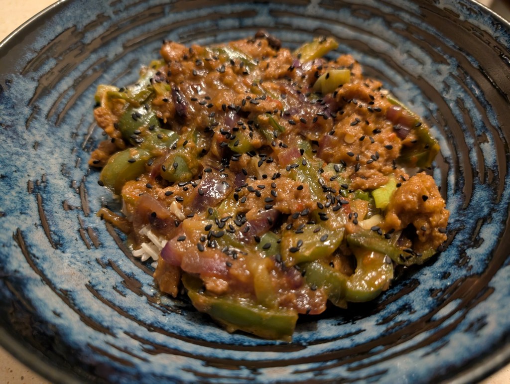 Rice topped with mock meat and green peppers in a sauce