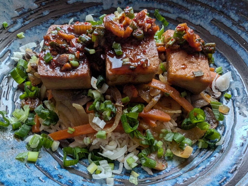 Rice topped with several slices of tofu and lots of garnishes