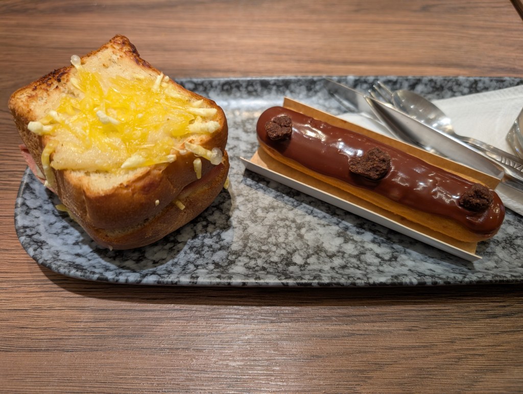 A plate with a croque monsieur and an eclair on it