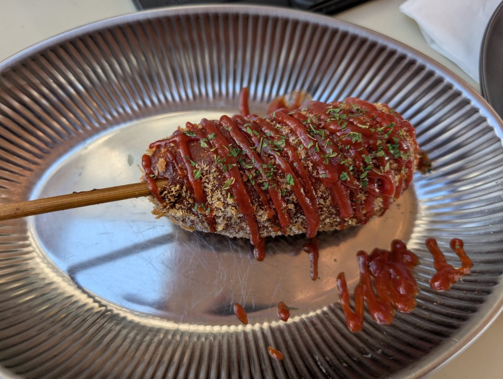 A corn dog drizzled with sauce