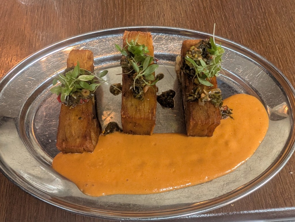 Three blocks of layered potato with an orange sauce and various garnishes