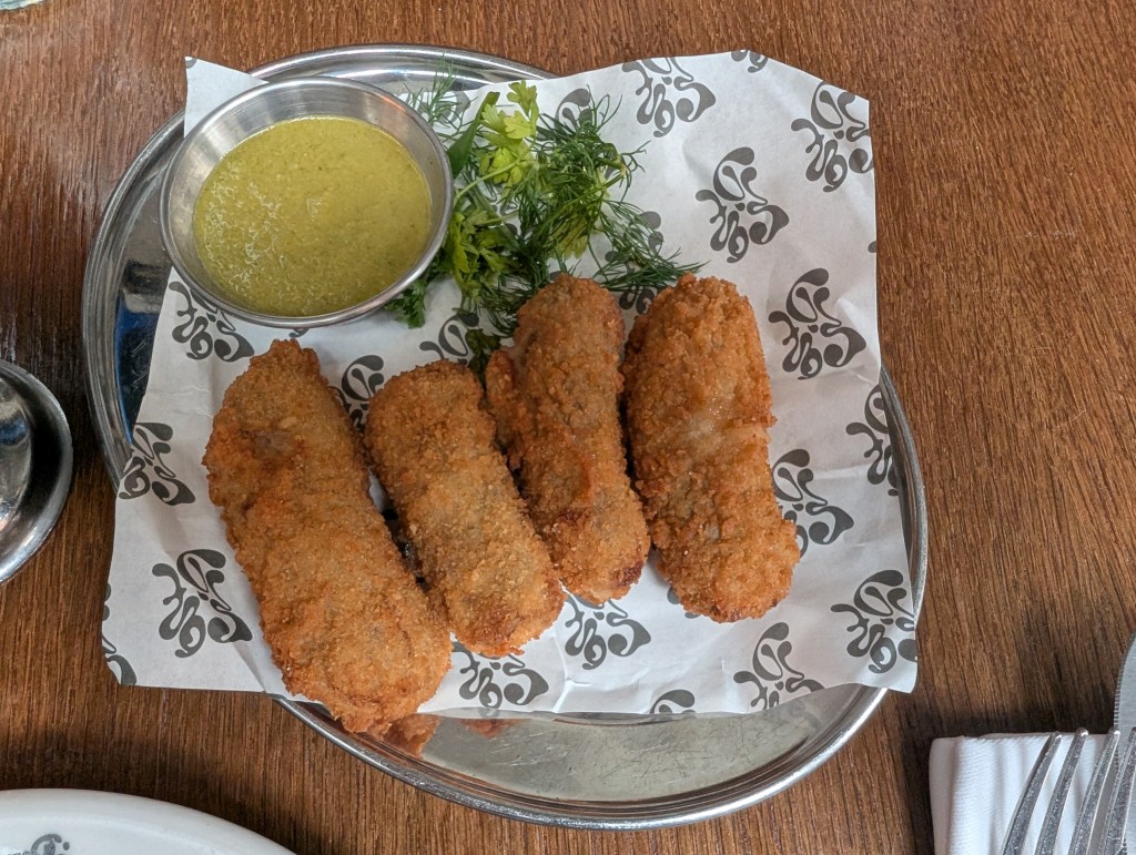 Four crispy croquettes with a green dipping sauce