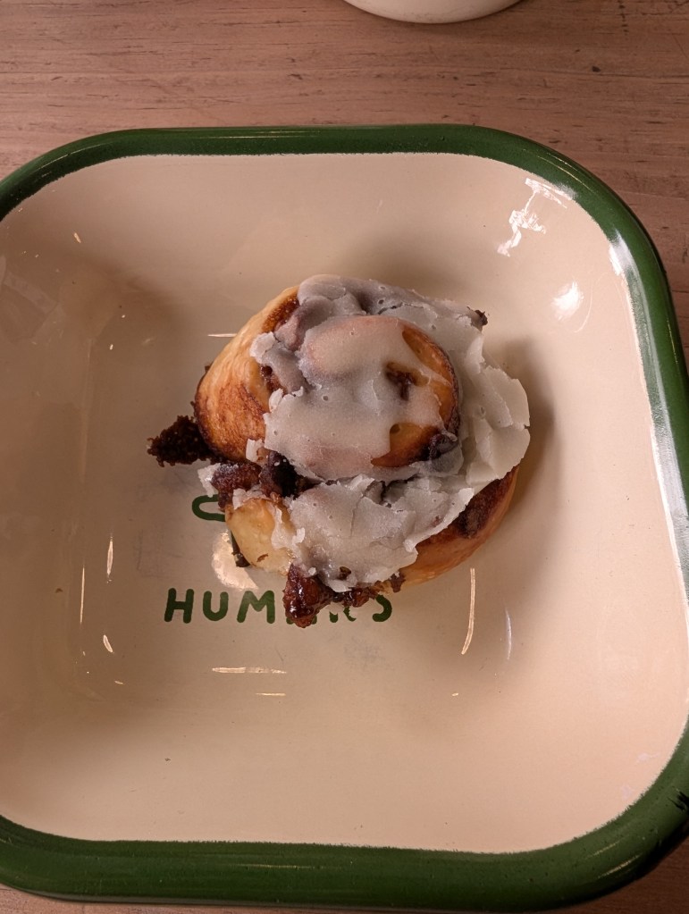 A very small cinnamon roll topped with icing 