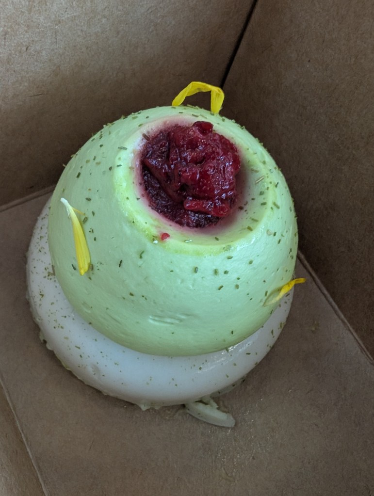 A white and green dessert in a takeaway box 