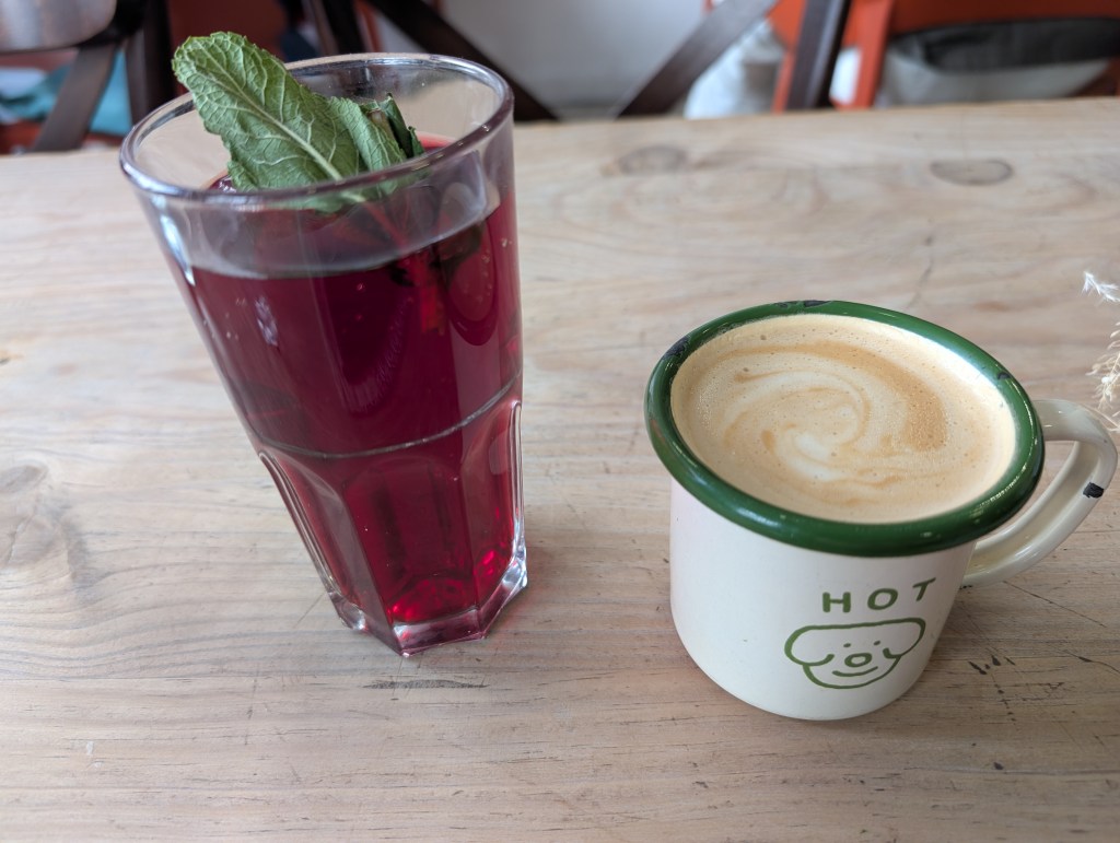 A tall glass of a cold red drink and a mug of milky coffee 