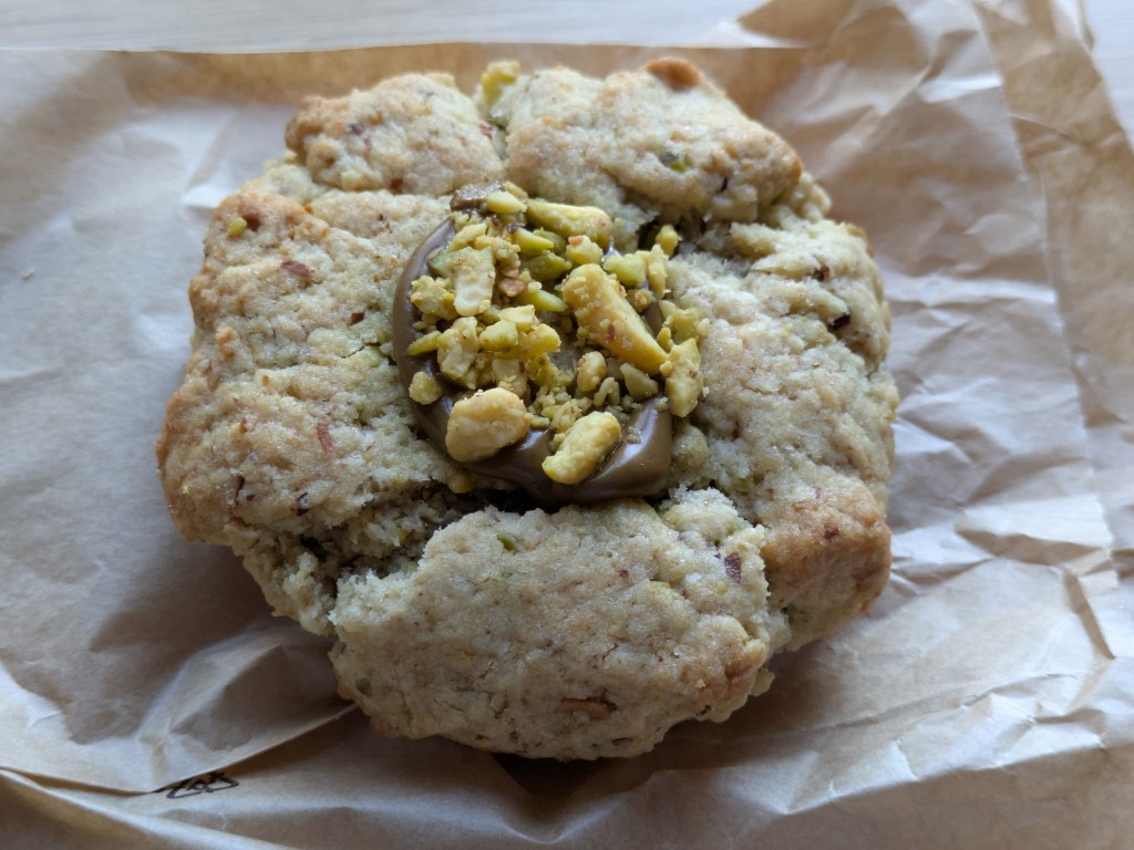 A cookie topped with chocolate spread and pistachios 