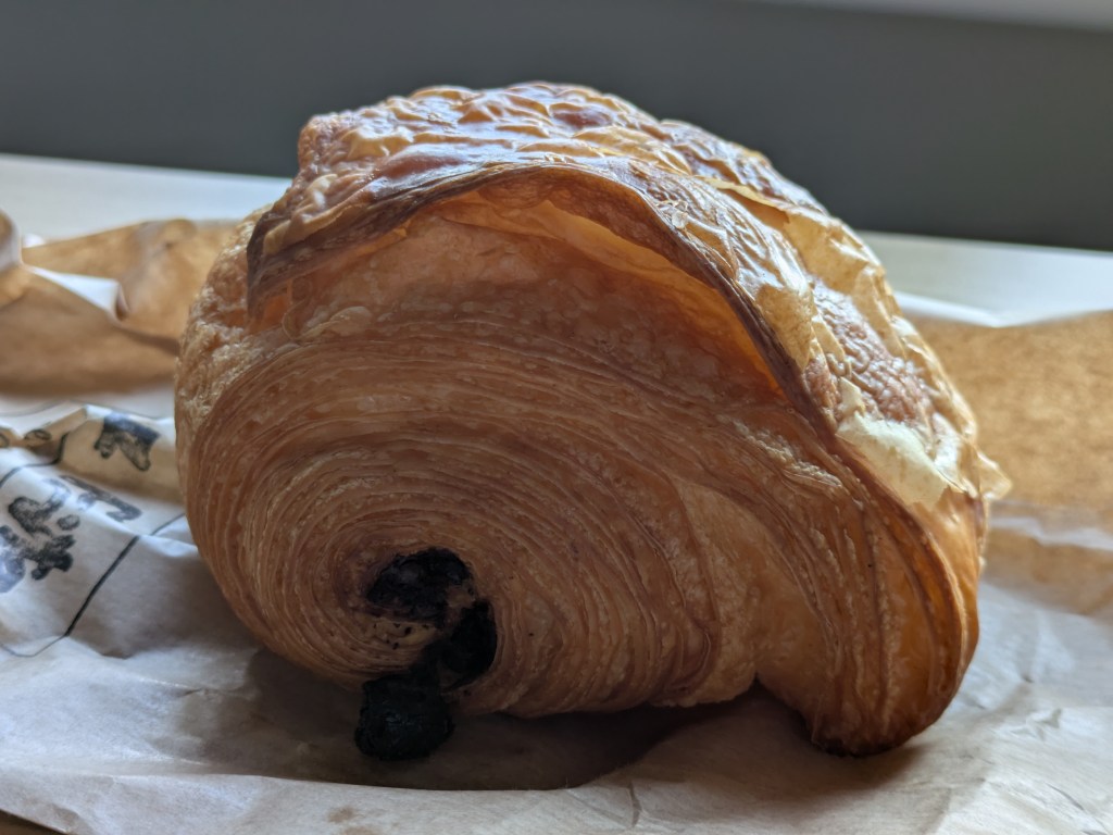 A side on view of a pain au chocolat with beautifully laminated pastry