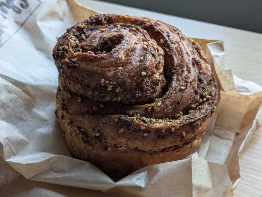 A pastry roll with za'atar liberally sprinkled on the top and through the rolls