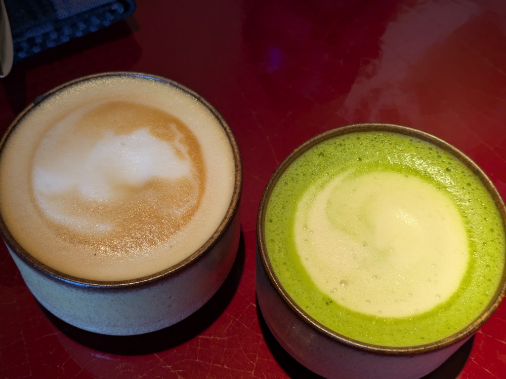 Two cups, one containing a cafe latte and the other a vivid green matcha latte