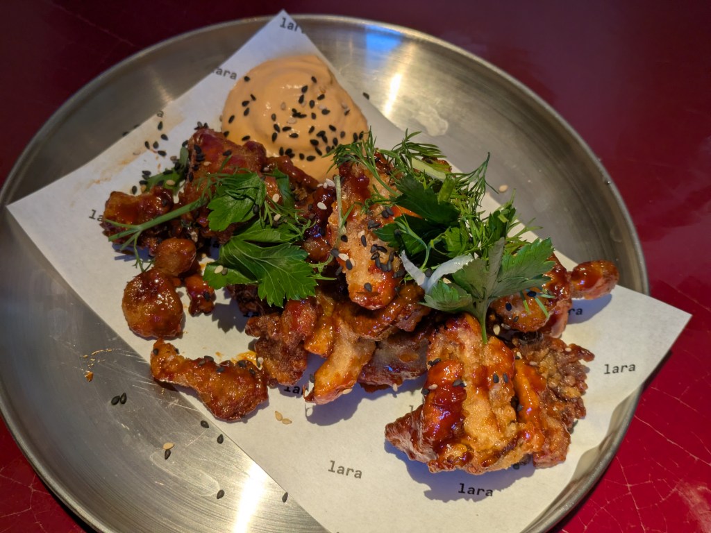 A bowl of fried mushrooms topped with fresh herbs and served with an orange coloured mayo