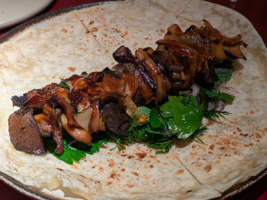 A tortilla topped with well cooked mushrooms and leafy herbs
