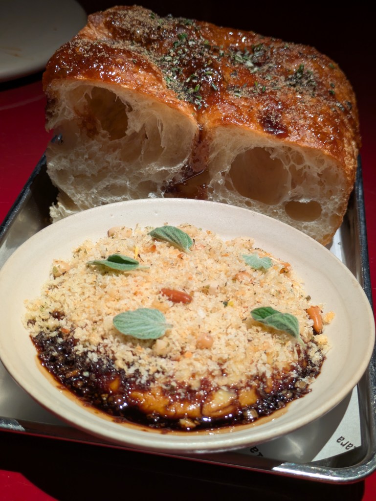 A large slice of focaccia behind a bowl of dip