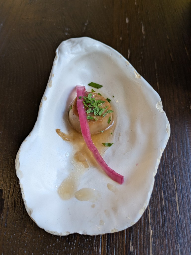 A piece of mushroom dressed with a little sauce and herbs, served in a shell