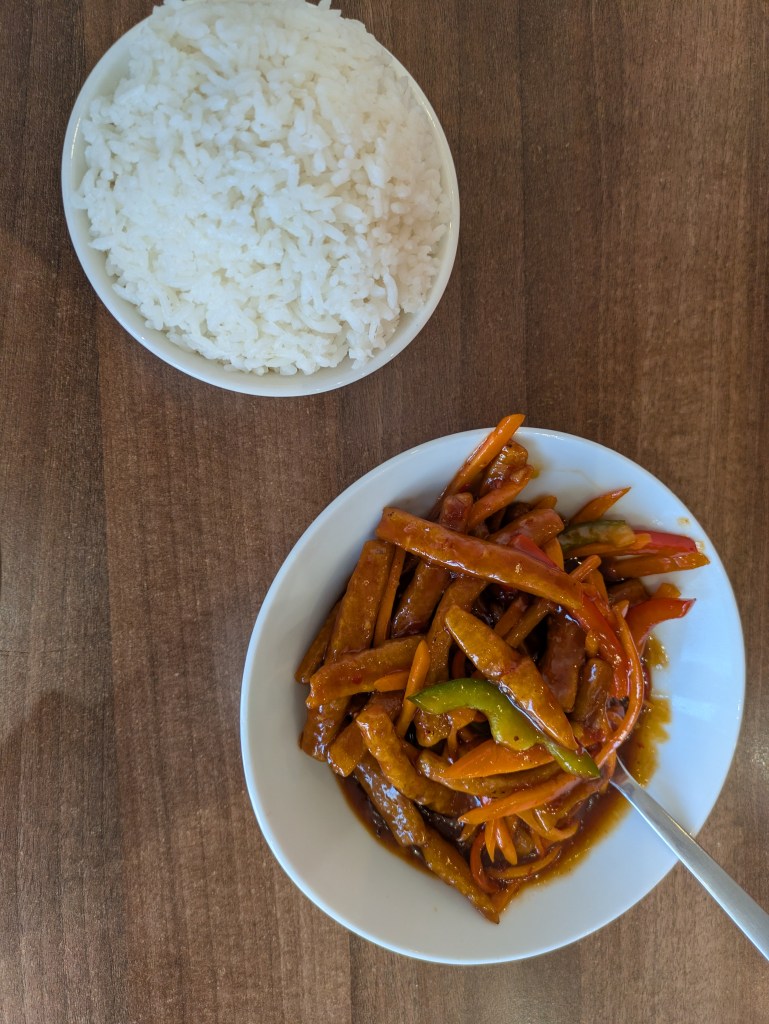 A bowl of rice and a bowl of strips of mock beef in a sticky looking sauce