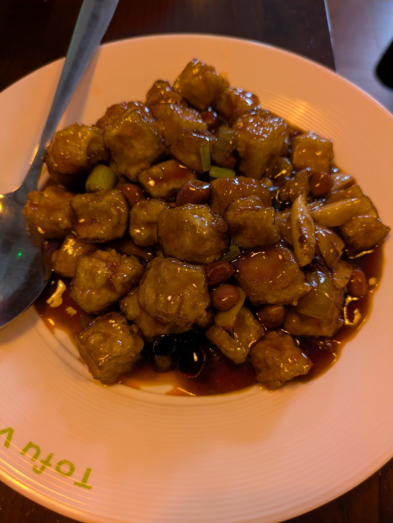 A dish of tofu and peanuts in a sticky sauce 