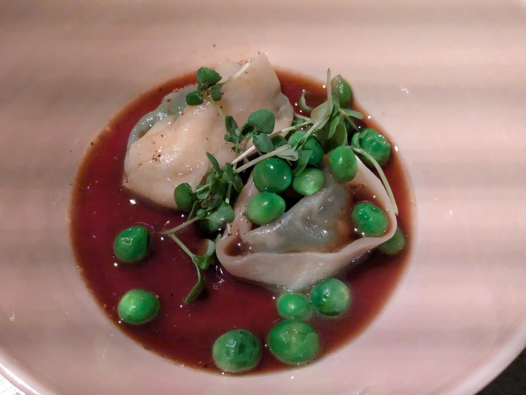 Two tortellini with peas in a brown broth