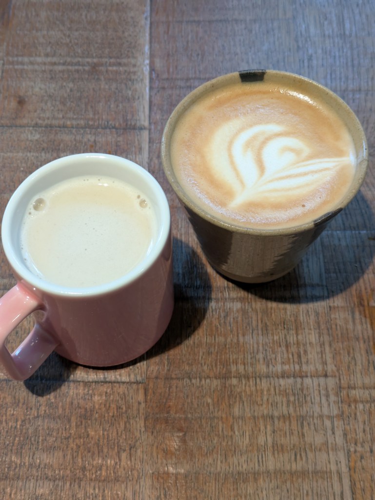 Two mugs of milky, foamy drinks