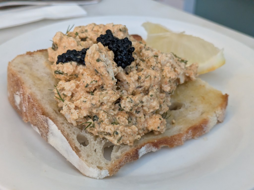A slice of toast topped with a crumbly tofu spread and some black caviar 