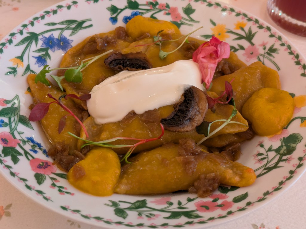 A bowl of Ukrainian dumplings with sauce, mushrooms and cream