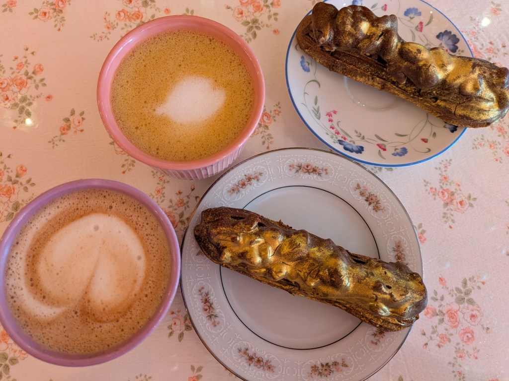 Two mugs of milky drinks, two eclairs