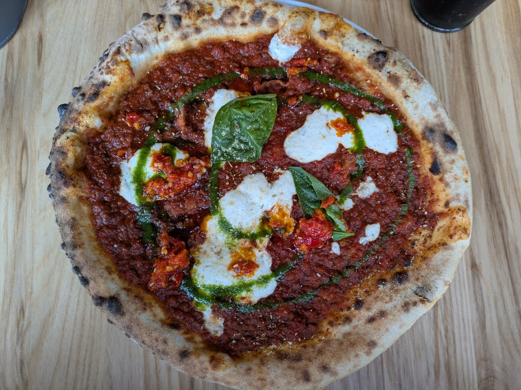 A lasagna piccante pizza with ragu sauce, cheese and basil