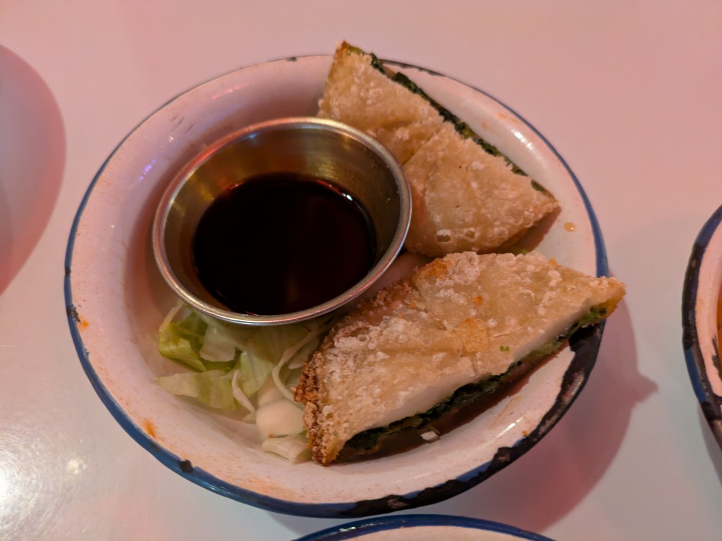 Two crispy rice cakes with dipping sauce