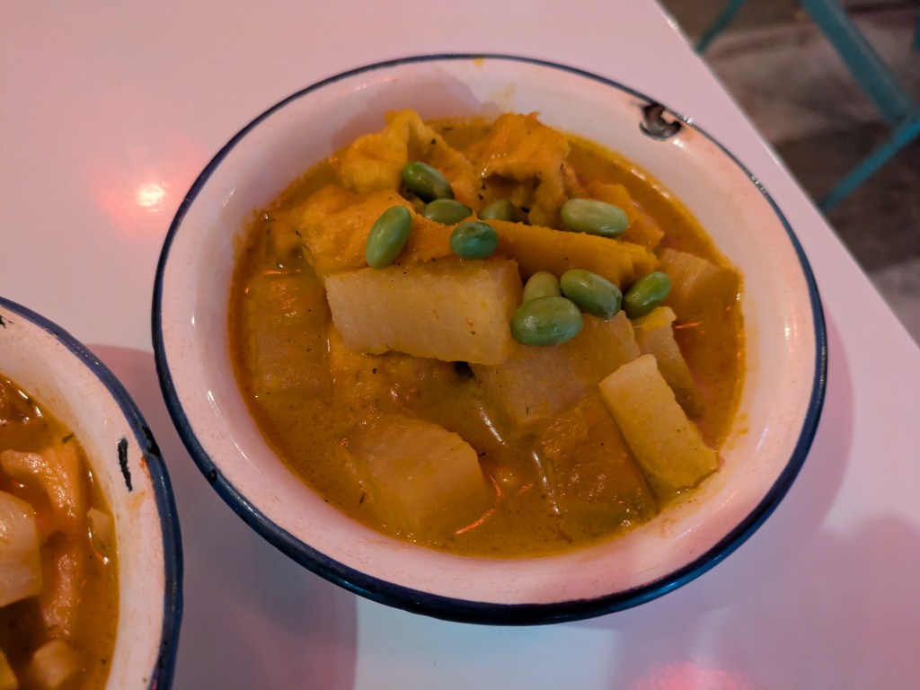 A bowl of yellow curry with vegetables 