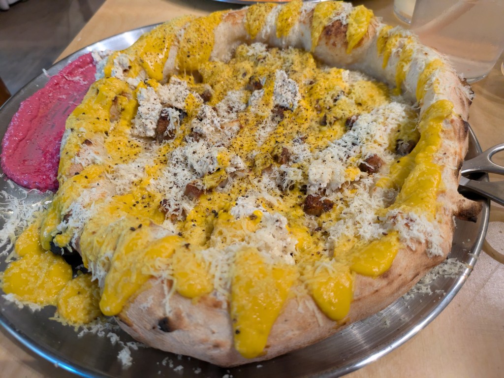 A pizza with lots of cheese and a yellow sauce