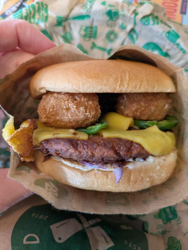 A beef burger topped with chilli cheese poppers and melted cheese 