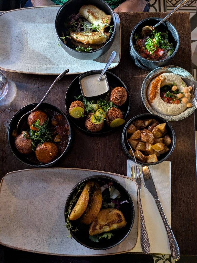A table with seven dishes of food for sharing