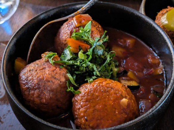 Three koftas in a bowl of tomato sauce