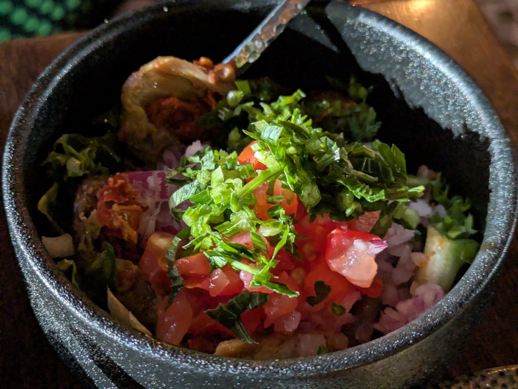 A bowl containing makdous buried under salad