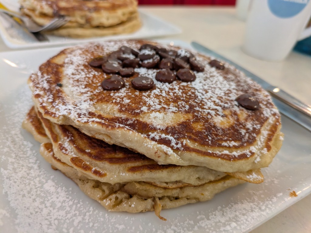 A stack of three pancakes topped with chocolate chips