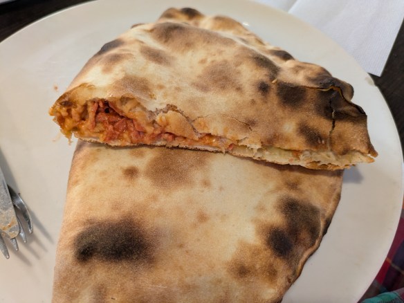 A calzone sliced in half to show the meaty, tomatoey filling